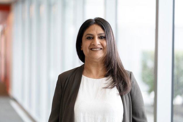 Portret van glimlachende zelfverzekerde Indiase zakenvrouw die in een modern kantoor staat