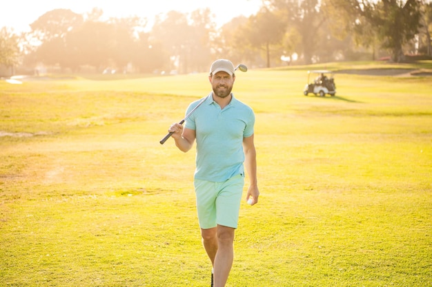 Portret van golfer in pet met golfclub lopen op groen gras golfen
