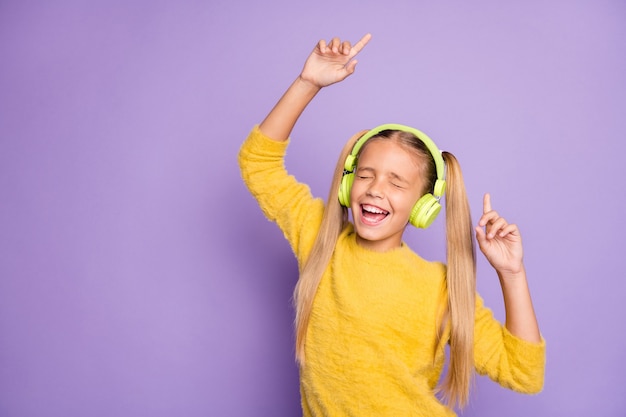 Portret van grappig funky gek kind pauze pauze veel plezier zingen lied gebruik groene koptelefoon luisteren muziek dans dragen stijlvolle trui geïsoleerd over paarse kleur muur