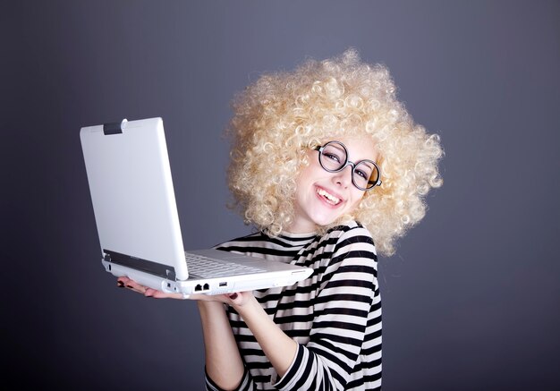 Portret van grappig meisje in blonde pruik met laptop.