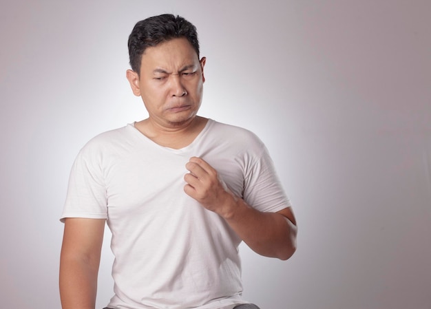 Portret van grappige jonge Aziatische man die zijn eigen lichaam ruikt slechte lichaamsgeur probleem