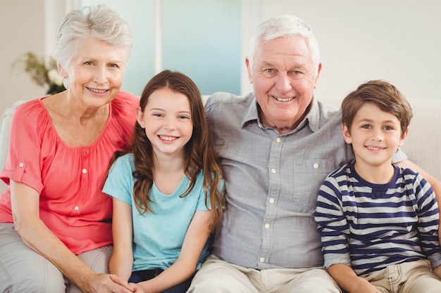 Portret van grootouders en kleinkinderen die samen op bank in woonkamer zitten