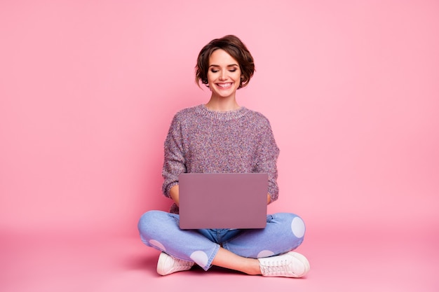 Portret van haar ze mooi aantrekkelijk mooi charmant vrij schattig vrolijk vrolijk bruinharig meisje zit in lotus houding met behulp van laptop e-mail typen geïsoleerd over roze pastelkleur muur