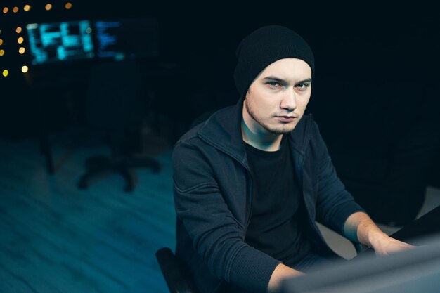 Portret van hacker met sweatshirt en pet probeert een beveiligingssysteem te hacken