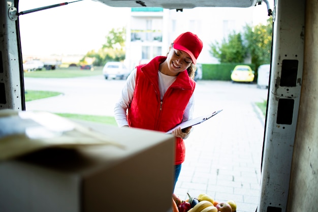 Foto portret van hardwerkende vrouwelijke koerier die pakketten schikt voor levering.