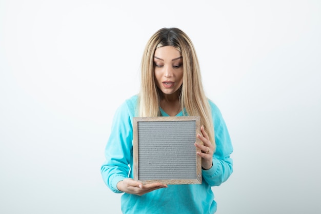 Portret van het aardig ogende frame van de dameholding tegen witte muur