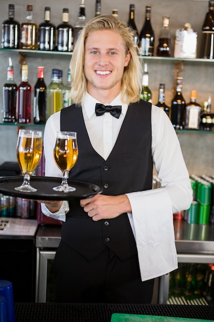 Portret van het dienblad van de kelnersholding met glazen bier