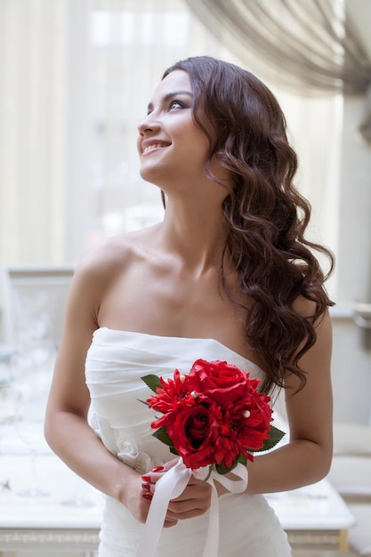 Portret van het gelukkige bruid stellen met rood boeket