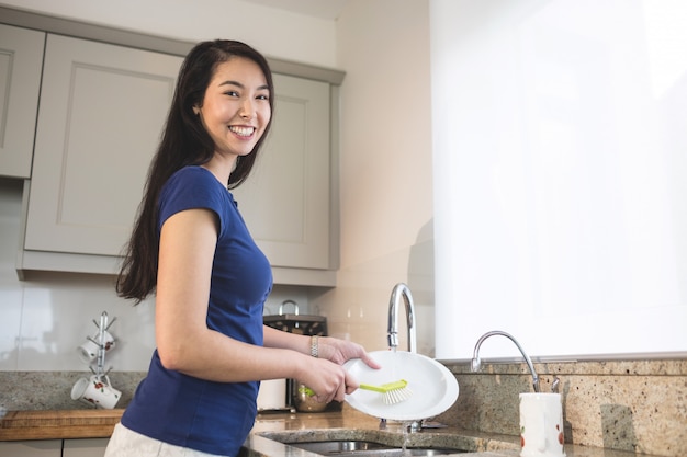 Portret van het gelukkige vrouw wassen in de keuken