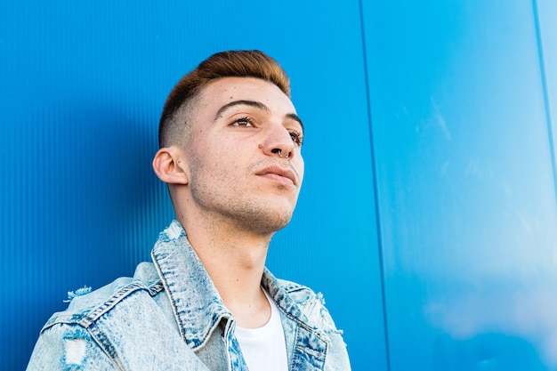 Portret van het gezicht van een geïsoleerde jonge en knappe man die ernstig in blauw kijkt