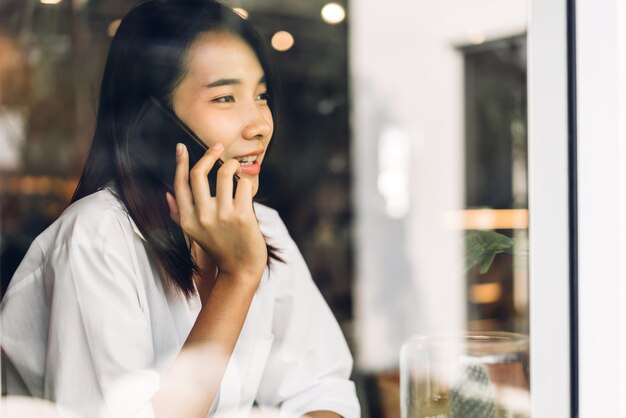 Portret van het glimlachen gelukkig mooie Aziatische vrouw ontspannen met behulp van digitale smartphone.