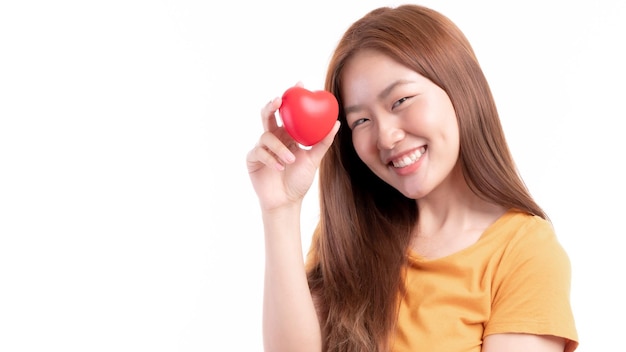 Portret van het glimlachen van een mooie Aziatische jonge vrouw met rood hart in de hand op witte achtergrond Valentine dag concept