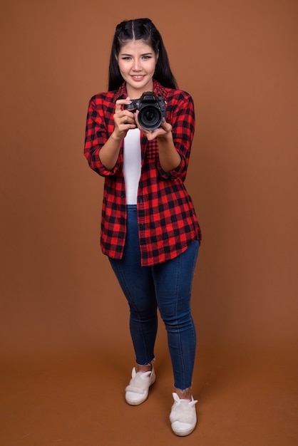 Portret van het jonge mooie Aziatische vrouwenfotograaf glimlachen