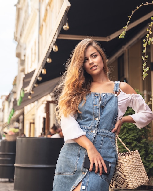 Portret van het jonge vrouw breed glimlachen terwijl het houden van smartphone openlucht wandelen