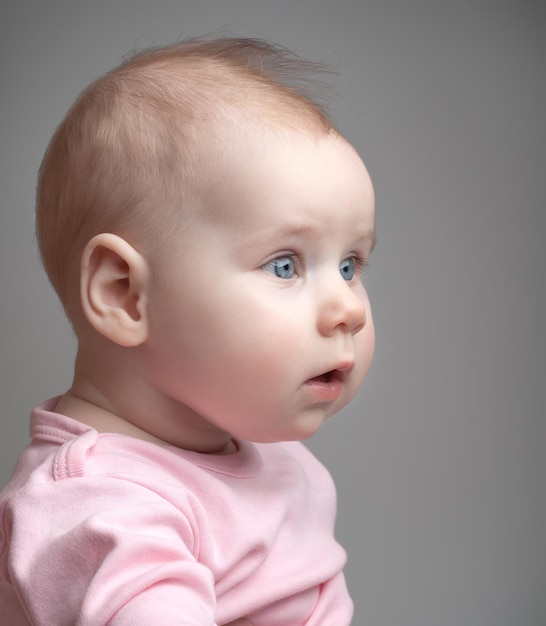 Portret van het kleine mooie meisje op een grijze achtergrond