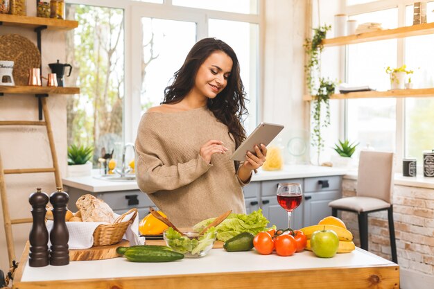 Portret van het koken van gezonde voeding jonge vrouw in de keuken op zoek naar een recept op het internet. Tabletcomputer gebruiken.