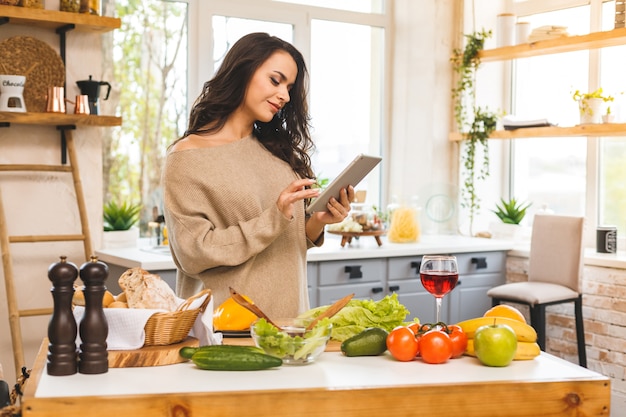 Portret van het koken van gezonde voeding jonge vrouw in de keuken op zoek naar een recept op het internet. tabletcomputer gebruiken.