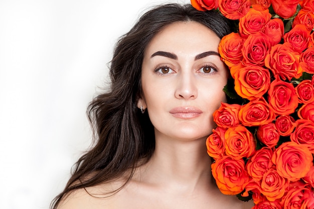 Portret van het lachende roodharige meisje met oranje rozen