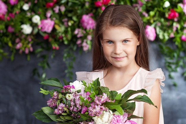 Portret van het mooie kleine meisje met een boeket bloemen.