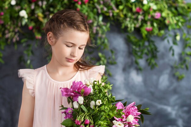 Portret van het mooie kleine meisje met een boeket bloemen.