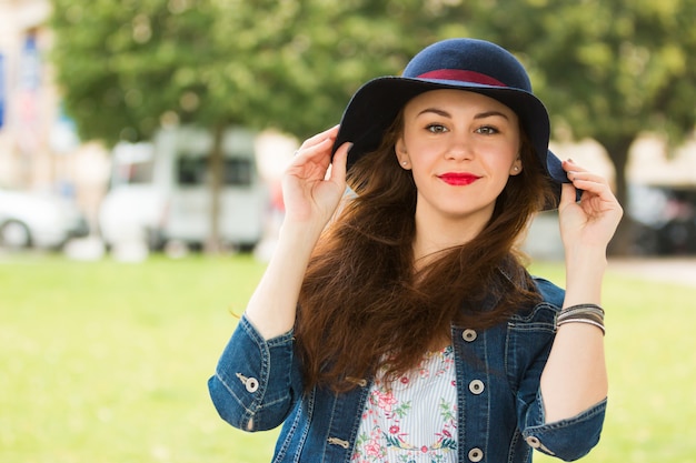 Portret van het mooie modieuze meisje met hoed buiten op zomerdag