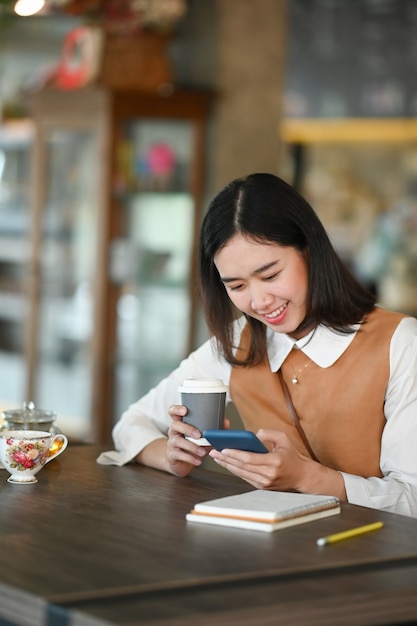 Portret van het vrolijke jonge studentvrouw ontspannen in coffeeshop