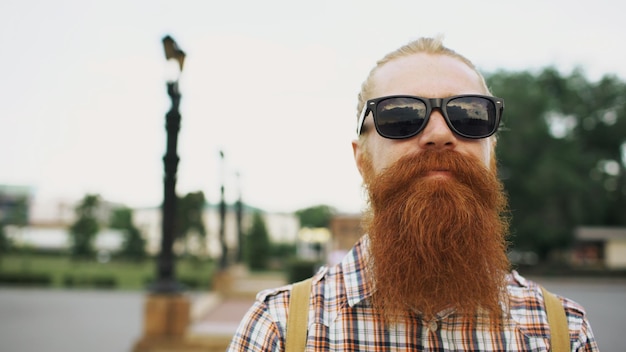 Foto portret van hipster bebaarde toeristische man in zonnebril camera kijken en glimlachen naar city