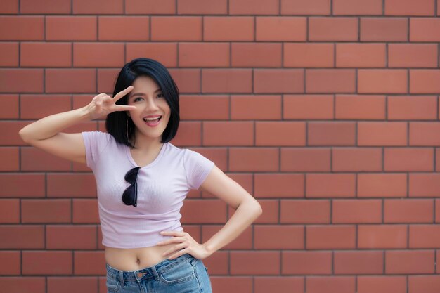 Portret van hipster meisje op bakstenen muur achtergrond Mooie aziatische vrouw poseert voor het nemen van een foto
