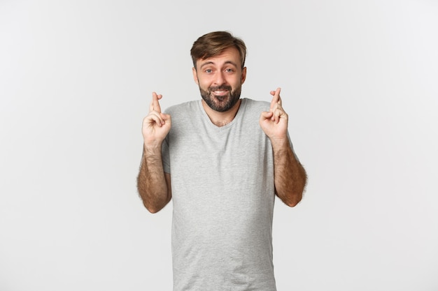 Portret van hoopvolle glimlachende man met baard, grijs t-shirt dragen