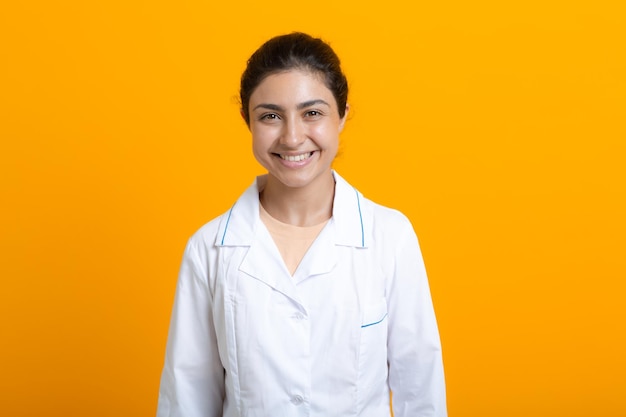 Portret van Indiase arts vrouw in witte medische jurk geïsoleerd op gele achtergrond