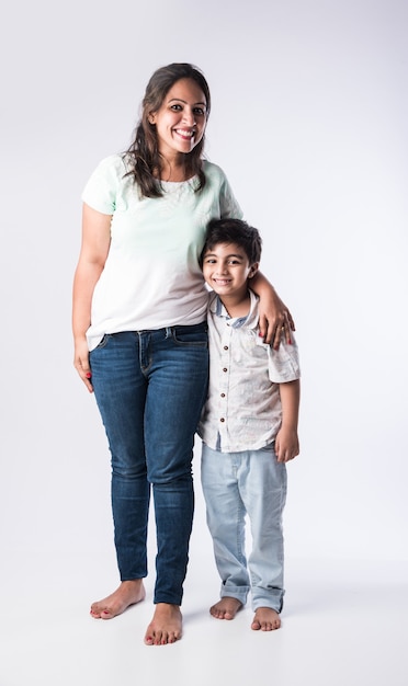 Portret van Indiase jonge moeder en zoon tegen een witte achtergrond, kijkend naar de camera