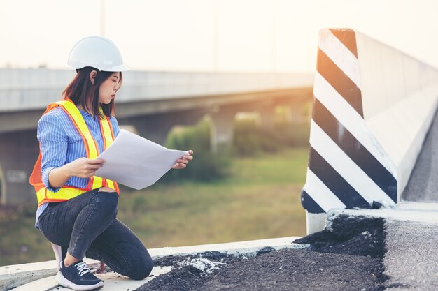 Portret van ingenieur gebaren over beschadigde weg, wegwerkers inspecteren bouw