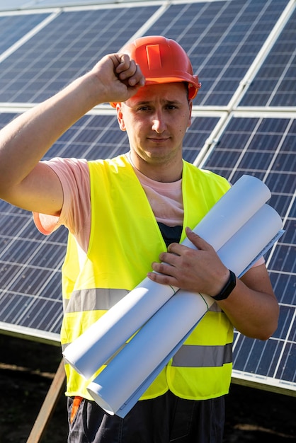 Portret van ingenieur met blauwdrukken poseren tegen zonnepanelen