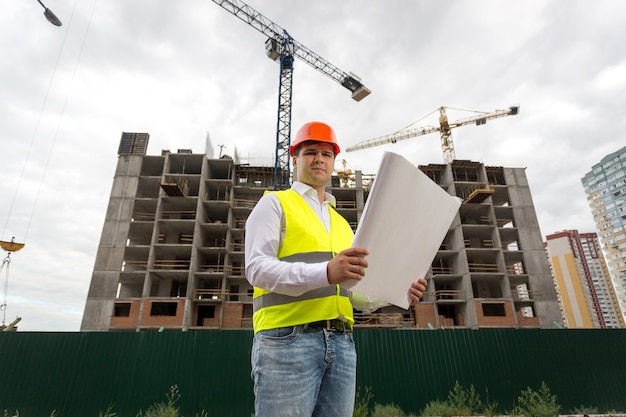 Portret van ingenieur op bouwplaats met blauwdrukken