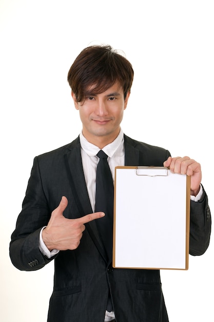 Portret van je Aziatische zaken man met lege notitie op witte achtergrond.