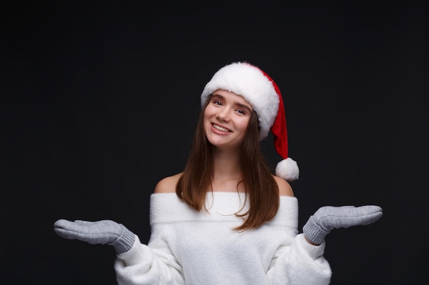 Portret van jong mooi glimlachend meisje in rode Kerstmanhoed met witte sneeuwvlokken