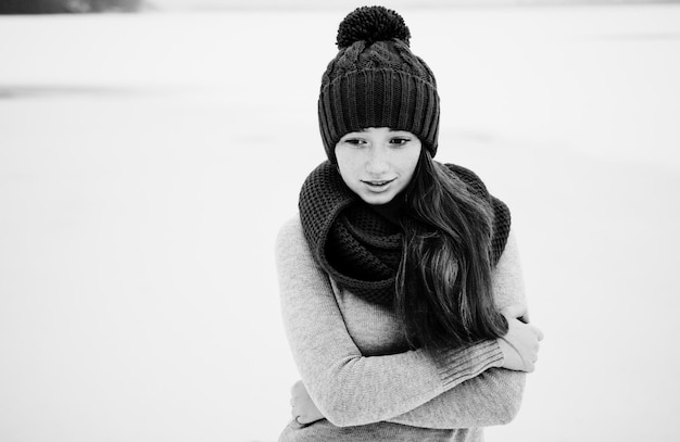 Portret van jong rood haar meisje met sproeten dragen op blauwe gebreide wollen muts en sjaal in winter dag achtergrond ijs zwart-wit foto