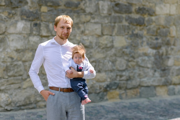 Portret van jong schreeuwend de babymeisje van de vaderholding over witte bakstenen muur