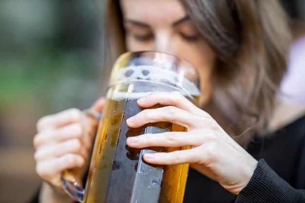 Portret van jong vrouw het drinken bier bij de bar