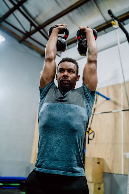 Portret van jonge atletische man doet oefening met crossfit kettlebel in de sportschool. Crossfit, sport en gezonde levensstijl.