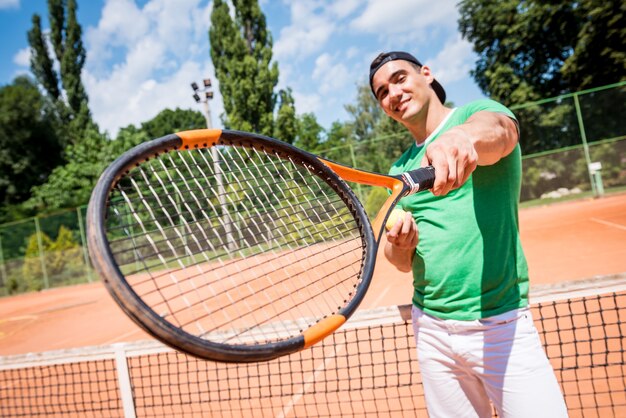 Portret van jonge atletische man op tennisbaan