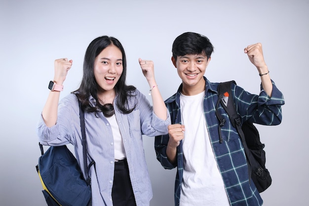 Portret van jonge Aziatische studenten in casual kleding met gesloten vuist die de overwinning vieren geïsoleerd over w
