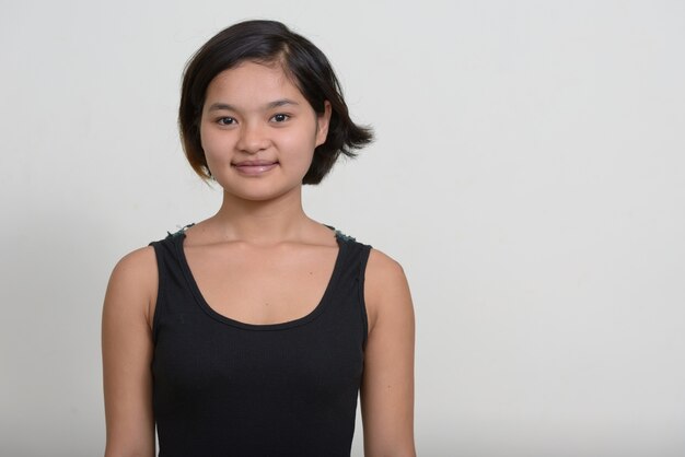 Portret van jonge Aziatische tiener met kort haar tegen witte muur