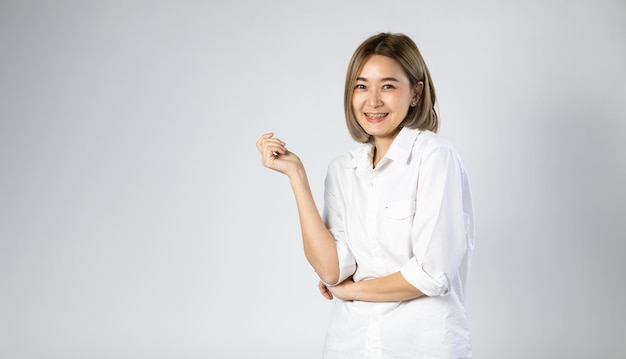 Portret van jonge aziatische vrij leuke vrolijke vrouw die beugels draagt en naar de camera kijkt op een witte achtergrond. natuurlijke make-up en witte tanden