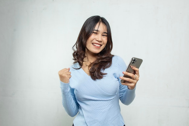 portret van jonge Aziatische vrouw gelukkig en enthousiast met smartphone die goed nieuws krijgt