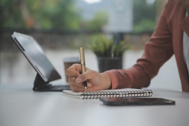 Portret van jonge Aziatische vrouw hand freelancer werkt haar baan op computertablet in modern kantoor Doen boekhoudkundige analyse rapport onroerend goed investeringsgegevens Financieel en fiscale systemen concept