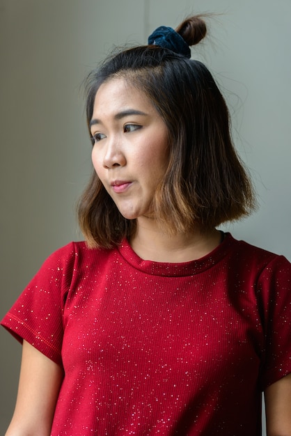 Foto portret van jonge aziatische vrouw met kort haar in de kamer bij het raam thuis