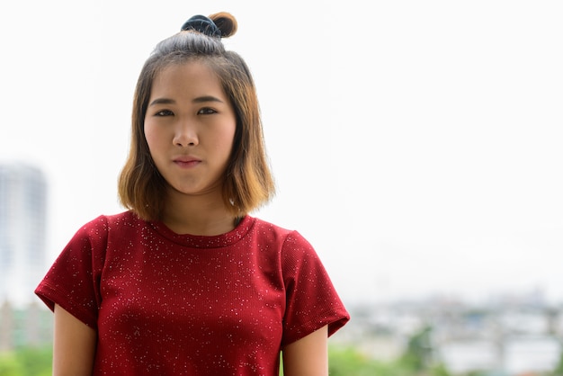 Portret van jonge Aziatische vrouw met kort haar tegen uitzicht over de stad buitenshuis