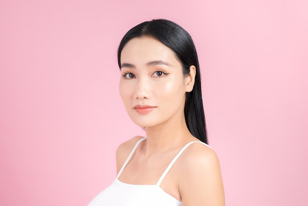 Portret van jonge Aziatische vrouw met perfecte huid op roze. Concept van natuurlijke cosmetica en huidverzorging.