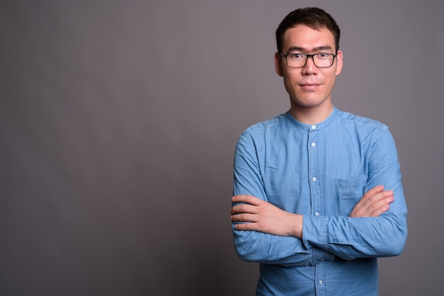 Portret van jonge Aziatische zakenman tegen grijze muur